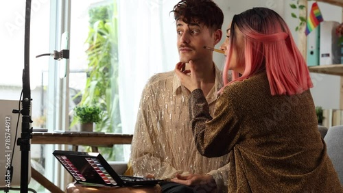 female friend puts makeup on her male friend while recording it for her social networks