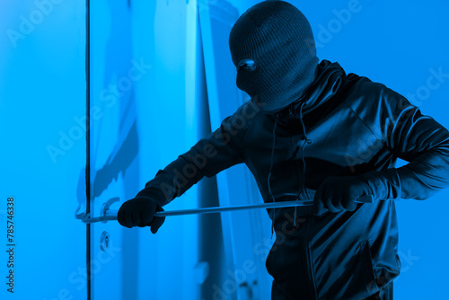 Intruder using crowbar on a door at night