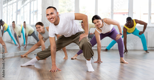 Positive Asian boy engaged in aerobic dance together with other attendees of dancing courses