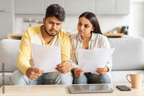 Couple reviewing financial papers with concern at home