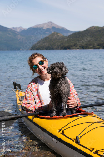 Beautiful woman kayaks with her best friend, her pet, a small dog who accompanies her.