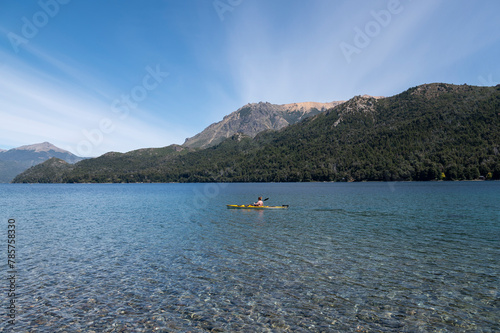 Cheerful young man enjoys kayaking while praying for the lakes of Bariloche during his summer vacation.