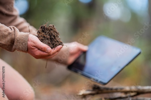 university student conducting research on forest health. farmer collecting soil samples in a test tube in a field. Agronomist checking soil carbon and plant health on a farm in australia