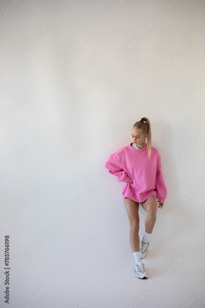 Beautiful blonde woman in pink hoodie and white panties posing on white background Beautiful blonde woman in pink hoodie and white panties posing on white background