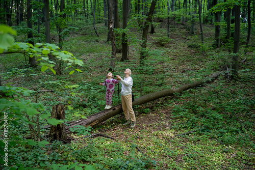 Mother and little girl looking for birds in forest, enjoying time in nature together 