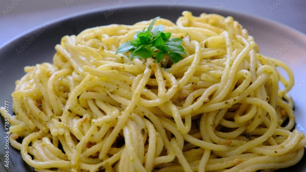 Spaghetti pasta with creamy pesto sauce on a 360-degree rotating black plate Spaghetti pasta with creamy pesto sauce on a 360-degree rotating black plate