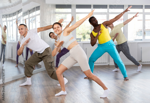 Positive young girl engaged in hip-hop dance together with other attendees of dancing courses