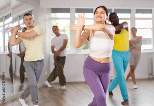 Active sporty multinational men and women of different ages practicing Hip-hop dance in training hall during dancing classes