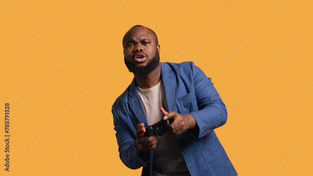 Portrait of cheerful BIPOC man playing videogames holding controller, studio background. Gamer smiling, having fun by participating in PvP online multiplayer game using console system, camera B