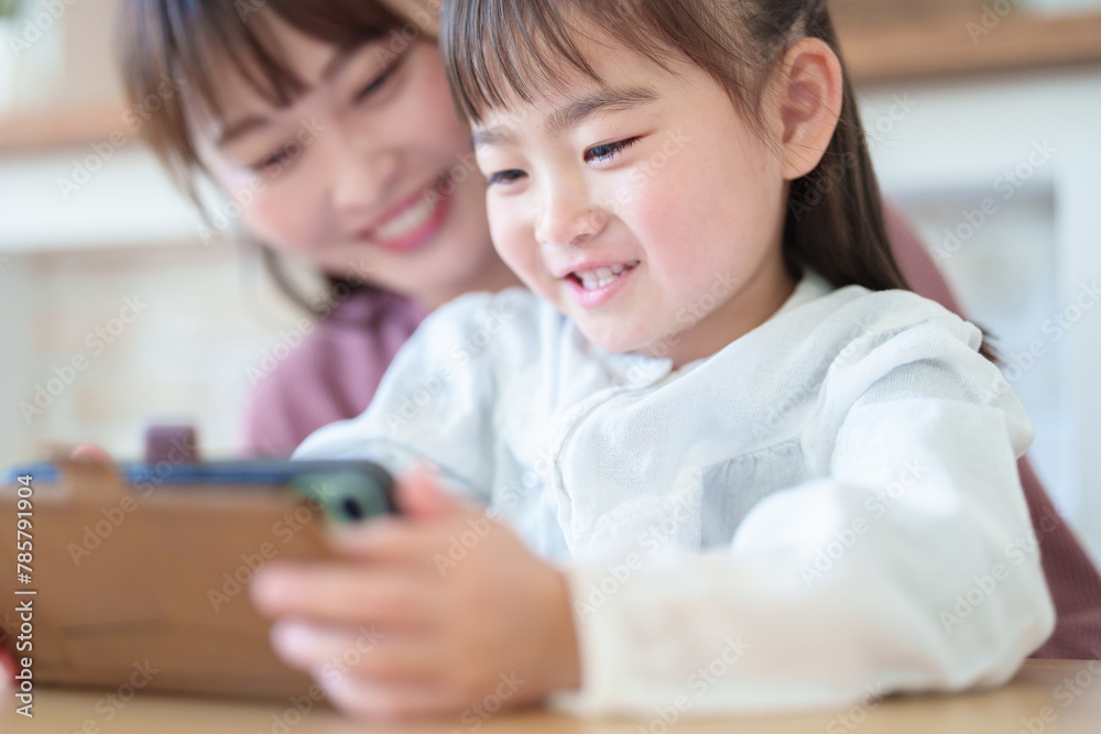 スマートフォンを使う親子 女の子とお母さん スマートフォンを使う親子 女の子とお母さん