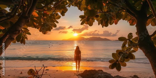 Serene sunset view with one person standing on tropical beach, orange sky, silhouette framed by tree leaves, vacation concept. photo