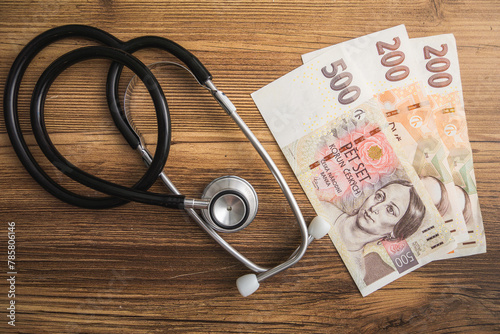 Stethoscope on Top of Pile of Czech crown banknotes, symbolizing financial aspects of healthcare 