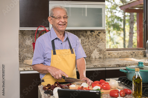 Portrait of an older adult man cooking in his home kitchen. photo