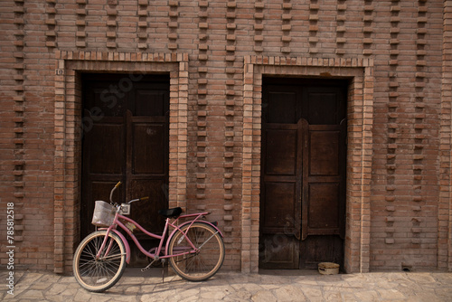 bicicleta retro color rosa enfrente de casa vieja de pueblo de viesca, coahuila  © XiX.Romero