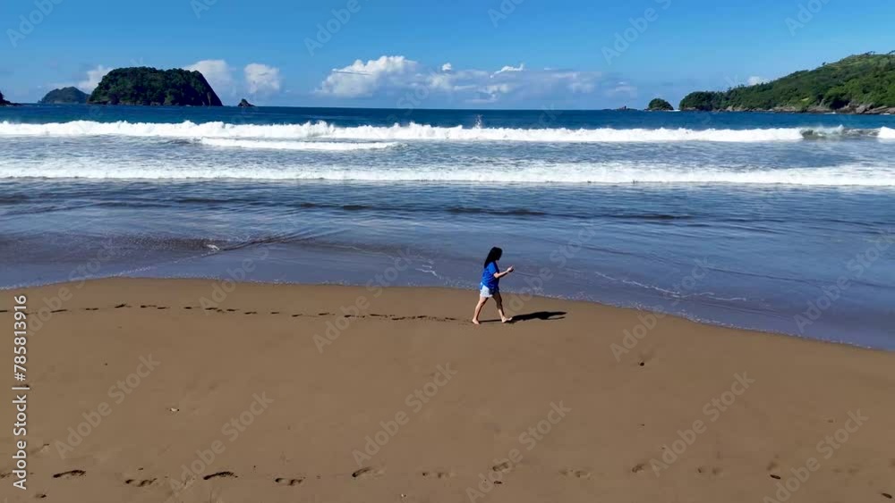 Asian woman with a beautiful face in casual clothes with shorts walking on the beach sand and playing in the waves. Asian woman with a beautiful face in casual clothes with shorts walking on the beach sand and playing in the waves.