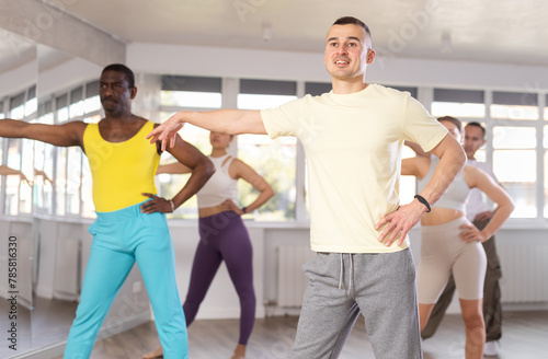 Positive man dancing and training movements Latin dance bachata during group class in choreography studio. Active lifestyle