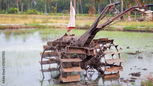 Rice field tractor machine on watery agricultural land in the countryside in Indonesia. photo