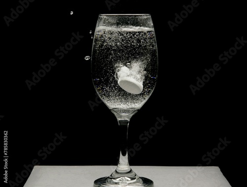 Alka seltzer dropped in a wine glass filled with water. photo