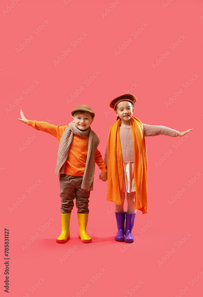 Little children in rubber boots on red background