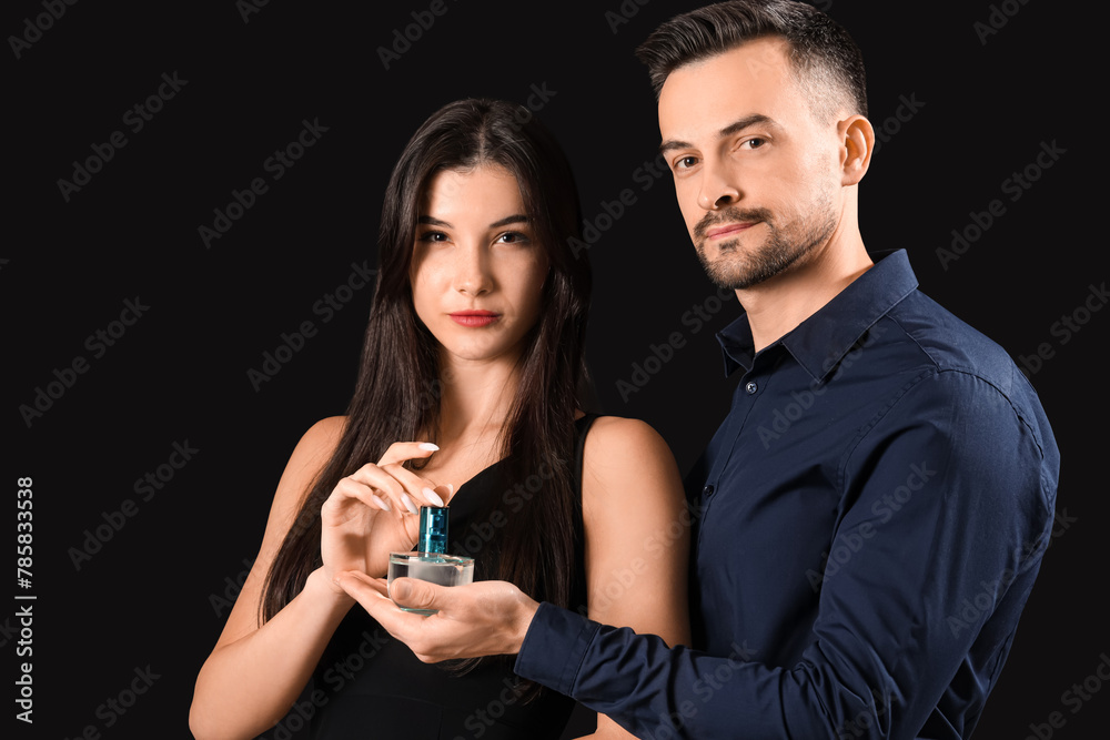 Young couple with perfume on dark background Young couple with perfume on dark background