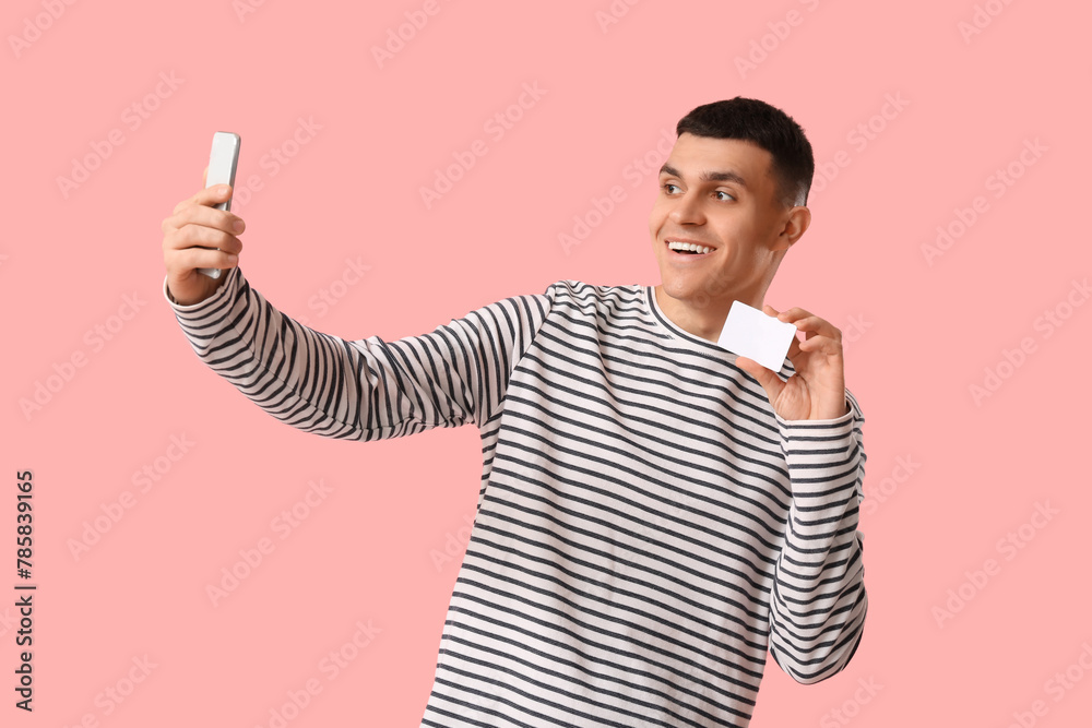 Young man with blank driving license taking selfie on pink background Young man with blank driving license taking selfie on pink background