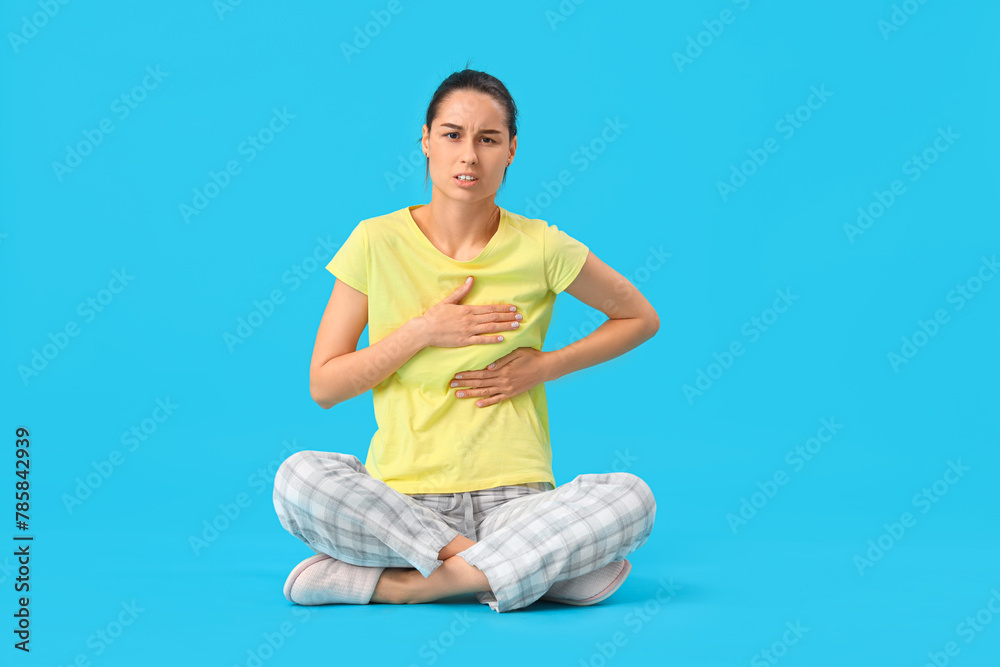 Young woman checking her breast on blue background. Cancer awareness concept Young woman checking her breast on blue background. Cancer awareness concept