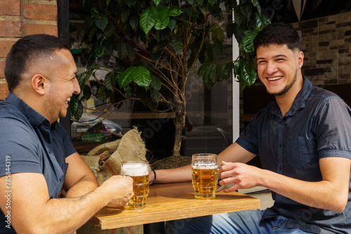 Two men are sitting at a table with two glasses of beer
