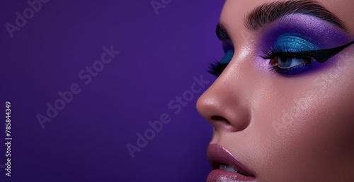 a woman s face with blue eyeshadow peeking out from the right side  with a purple background  for an eye makeup ad