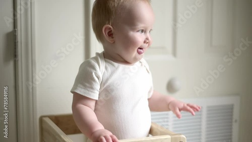 one year old blond hair  boy stands kitchen helper and claps, safety