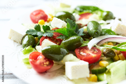 Healthy Salad with Feta Cheese, Green Olives, Baby Spinach, Cucumber, Cherry Tomatoes and Capers. Bright background. Close up.