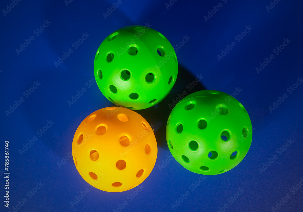 Colorful Pickleball ball in blue background. Pickleball is a new sport that is developing and starting to be popular with the public. Colorful Pickleball ball in blue background. Pickleball is a new sport that is developing and starting to be popular with the public.
