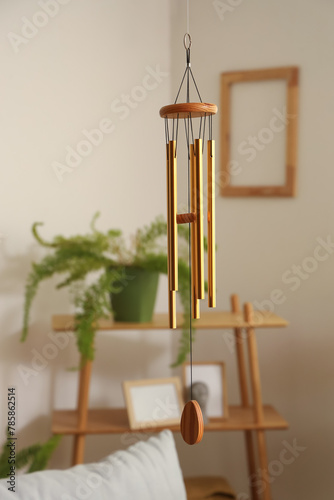 Obraz na plátně Golden wind chime hanging in light living room, closeup