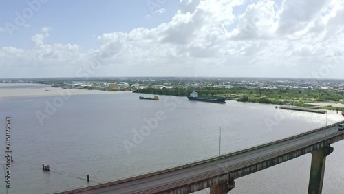 Close aerial shot of Jules Wijdenbosch Bridge between Paramaribo and Meerzorg in Suriname, South America, with traffic as drone orbits oil tanker ship photo