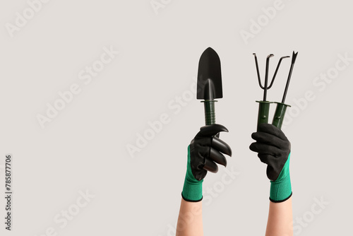 Female hands in gardening gloves with shovel, weeder and rake on white background. Gardening tools