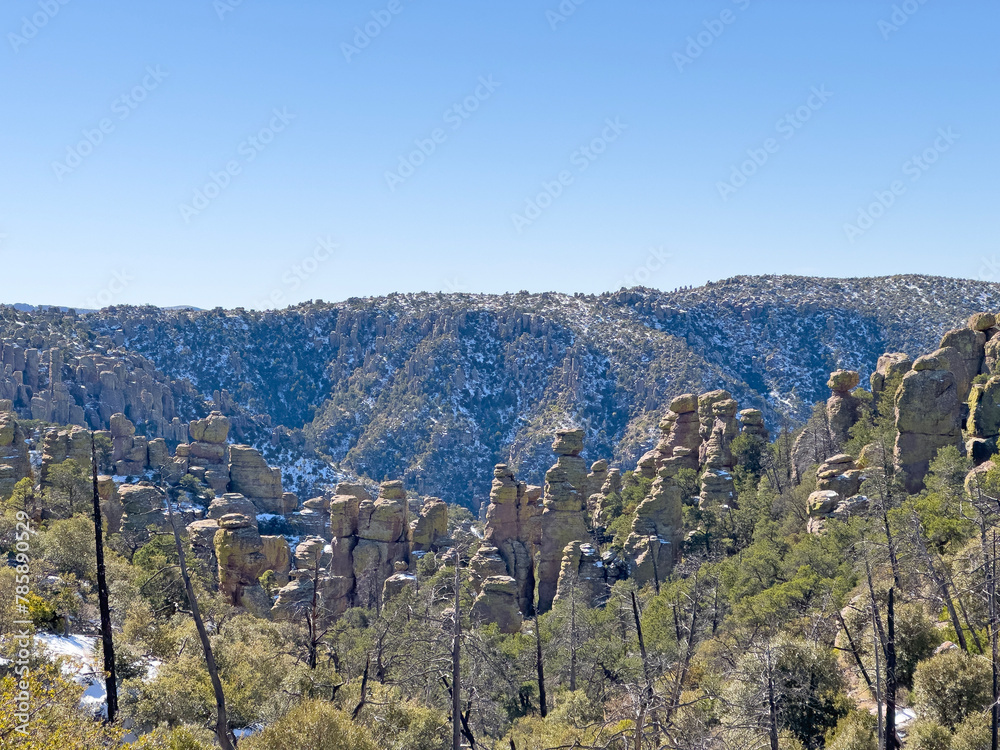 A clear blue sky above Chiricahua National Monument with its rock formations and green forest. Travel destination for Southwestern USA.