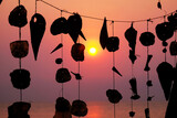 Silhouette of shells shape hanging on the rope with sunset background