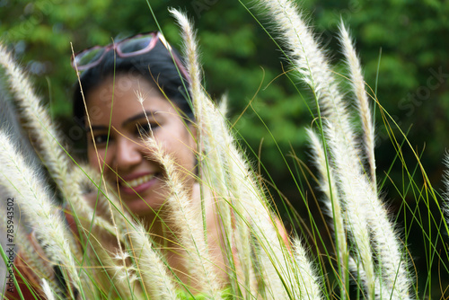 Beautiful young Indian woman behind grass in the grass field Giving the feeling of relaxation, relaxation and freedom