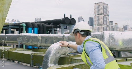A Engineer man looking inspecting maintenance insulated pipelines valve pump control on the roof at an industrial site, serious stressed face
