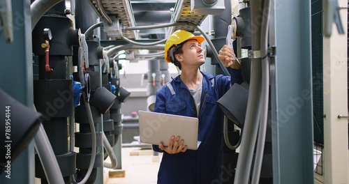 engineer using laptop checking industry cooling air conditioner water cooling tower air chiller of large industrial building to control air system at construction site