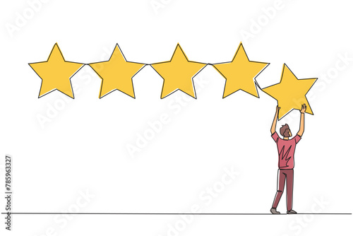 Continuous one line drawing young man stood holding up a star with both hands and pasting it up to make 5 stars in a row. Give the best review. Online shop. Single line draw design vector illustration