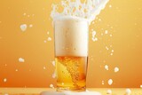Pouring beer into glass with splashes on orange background, closeup