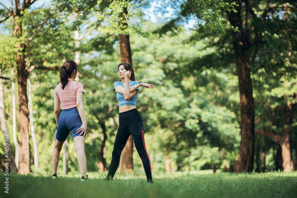 Fototapeta premium two Asian women engaging in physical activity within an urban park.