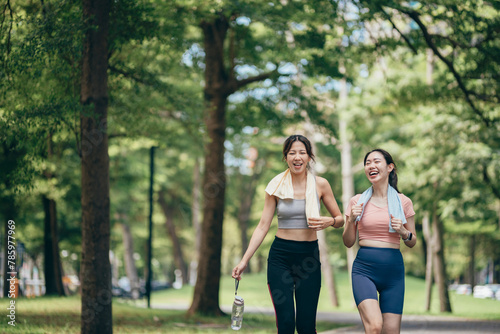 two Asian women engaging in physical activity within an urban park.