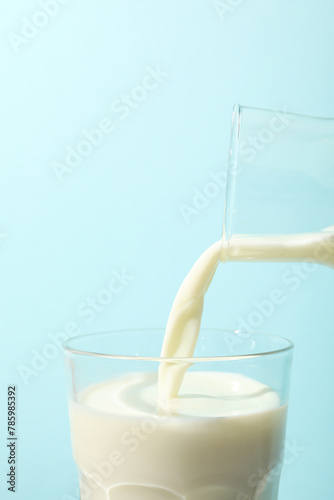 Bottle and glass with milk on blue background, close up