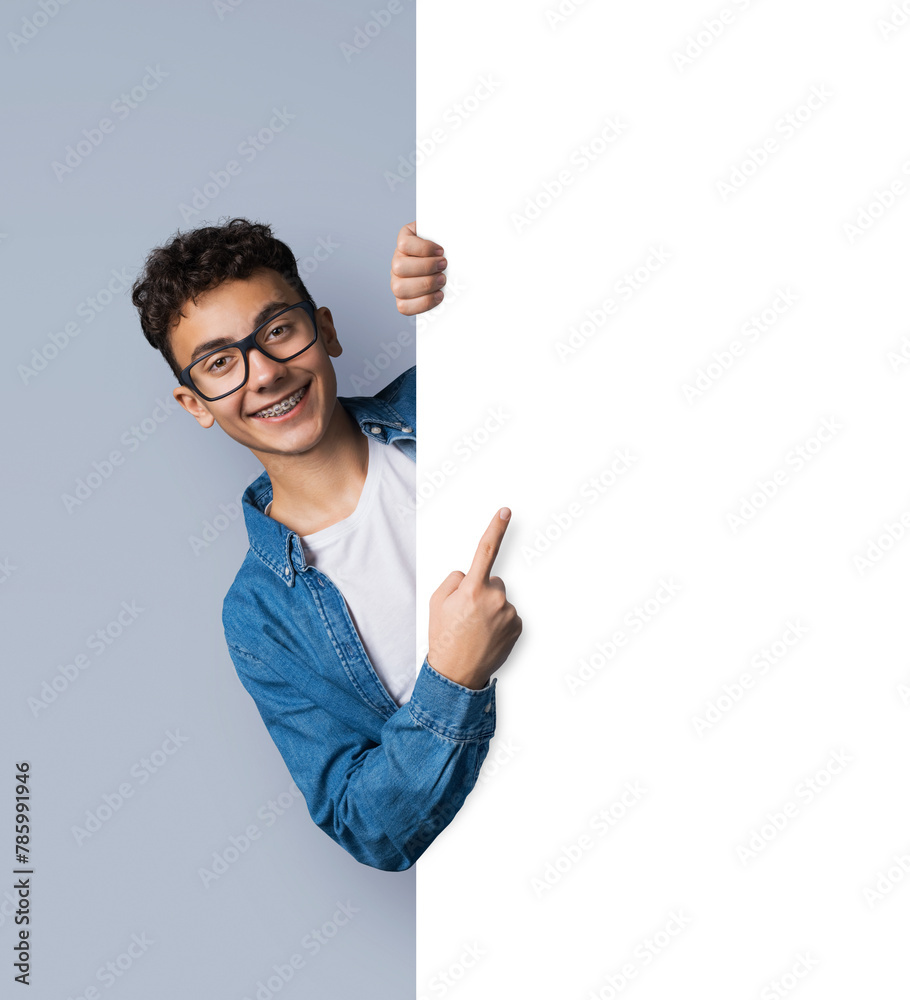 Excited happy man wear eye glasses, braces stand behind, peep from blank empty banner mockup sign board signboard, advertise show area for slogan text isolate grey gray background. Dental care Excited happy man wear eye glasses, braces stand behind, peep from blank empty banner mockup sign board signboard, advertise show area for slogan text isolate grey gray background. Dental care