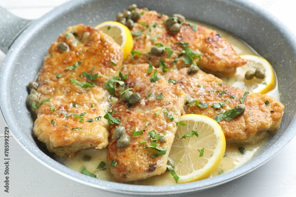 Delicious chicken piccata with herbs and lemons on table, closeup