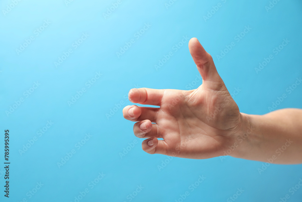 Woman holding something in hand on light blue background, closeup. Space for text Woman holding something in hand on light blue background, closeup. Space for text