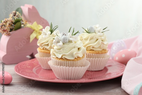 Tasty Easter cupcakes with vanilla cream on wooden table