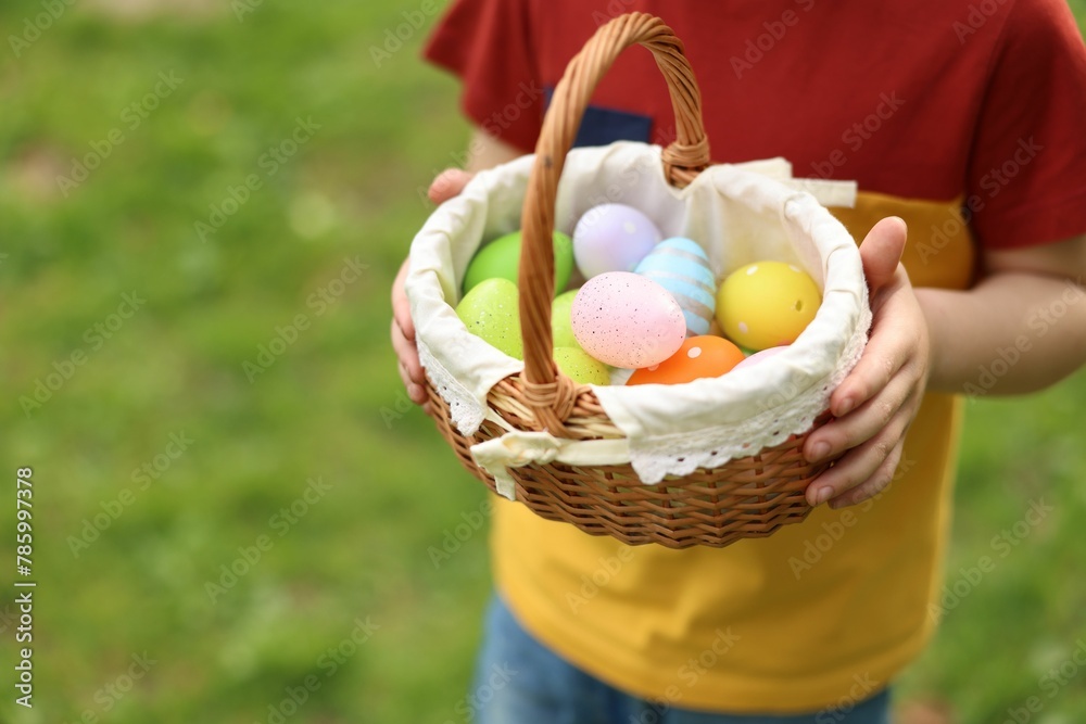 Easter celebration. Little boy holding basket with painted eggs outdoors, closeup. Space for text Easter celebration. Little boy holding basket with painted eggs outdoors, closeup. Space for text