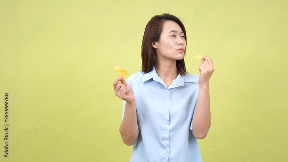 Young Asian woman eating snack on green background Young Asian woman eating snack on green background